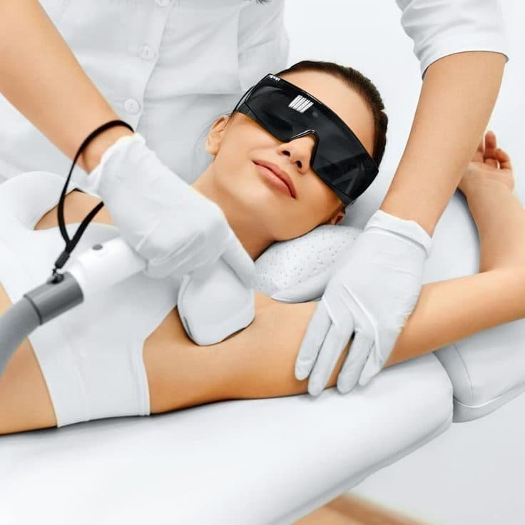 Therapist performing a laser hair removal session on a client wearing protective eyewear
